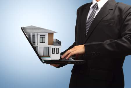 real estate agent holding a laptop with house on top